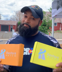 A man is holding two Restore Patch boxes: on his left hand, a Clarity-Focus Patch, and on his right hand, an Energy Patch.