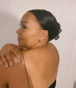 Load image into Gallery viewer, An image showing a woman facing slightly backwards while touching a Restore patch placed on her right shoulder.
