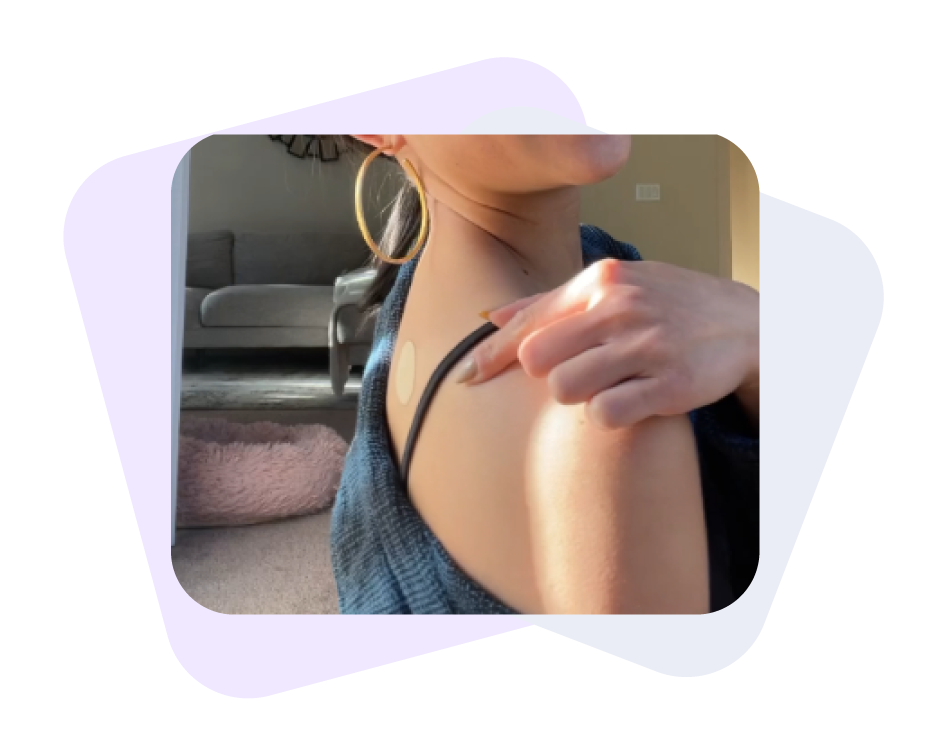 Image of a woman pointing at her right shoulder where a Restore patch is applied.