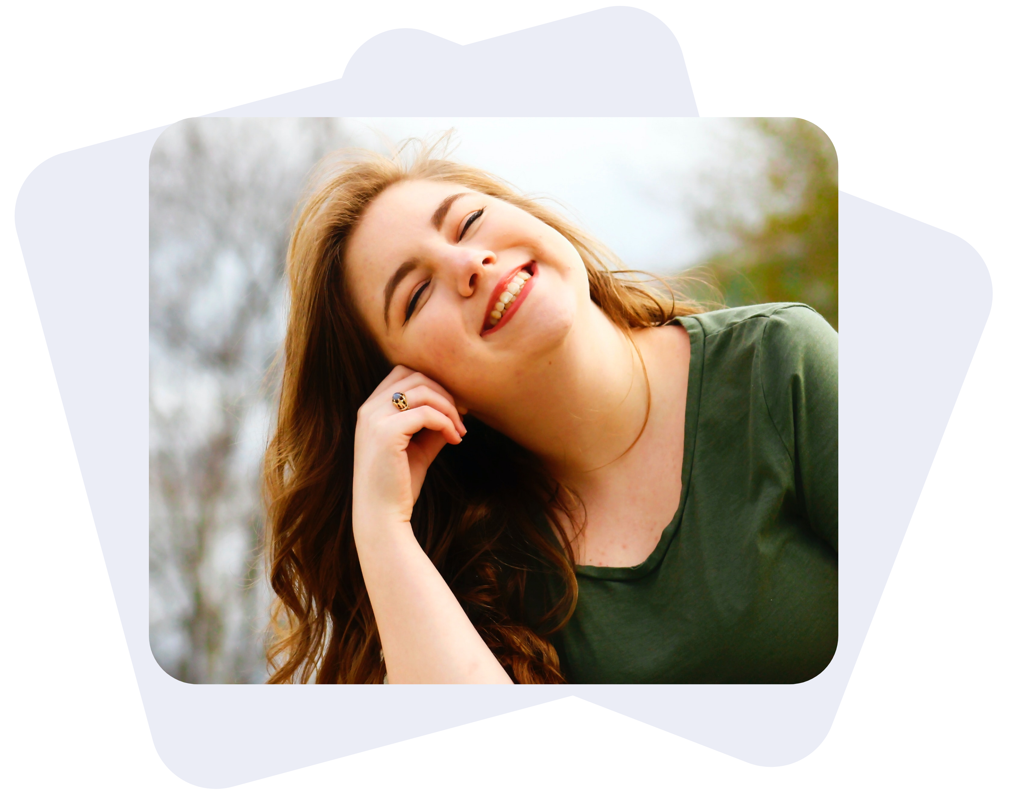 A woman wearing an olive green blouse is tilting her head on her right side while smiling with her eyes closed.